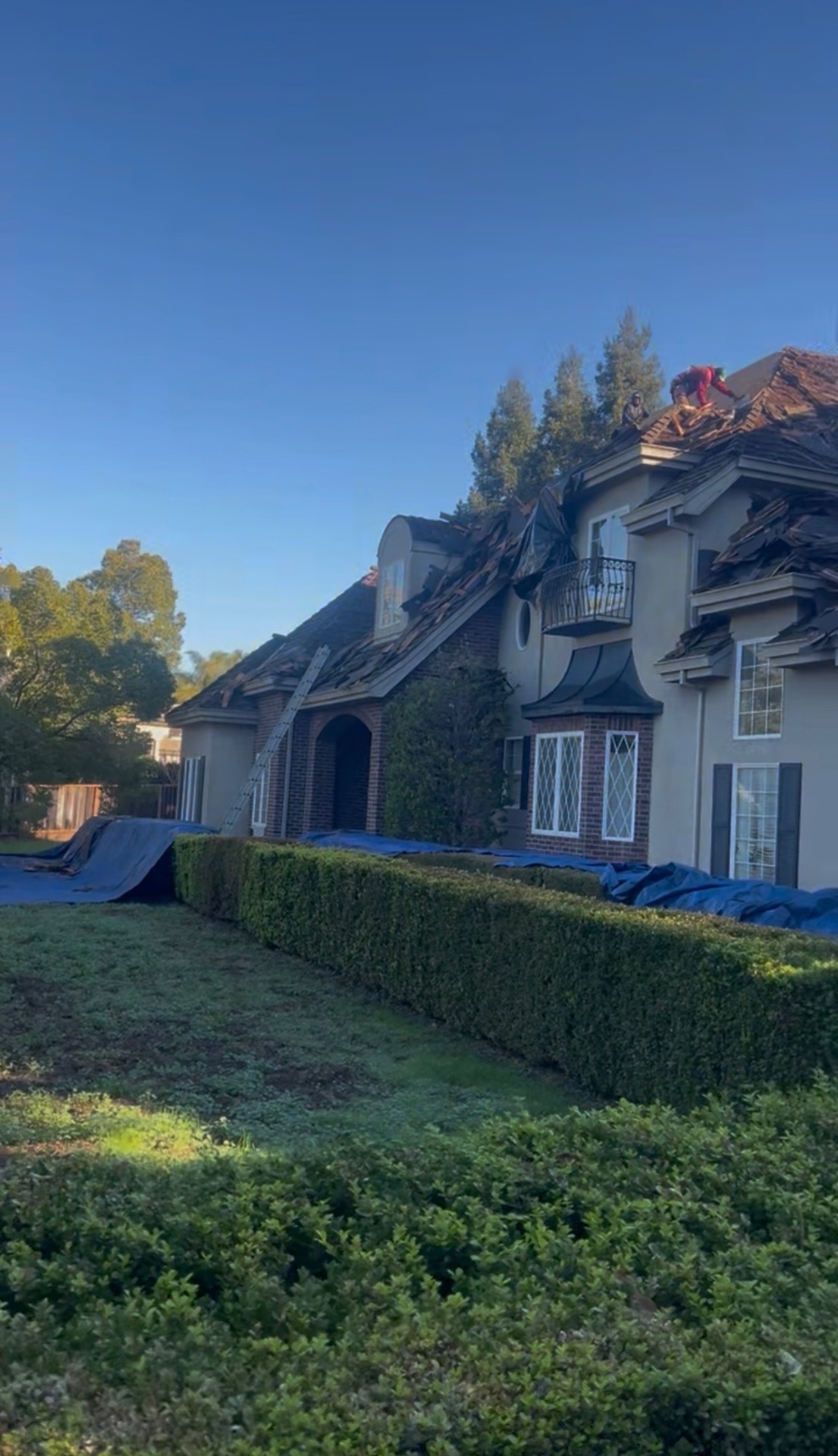 Full exterior view of a Los Angeles Tudor estate during a complete roof replacement