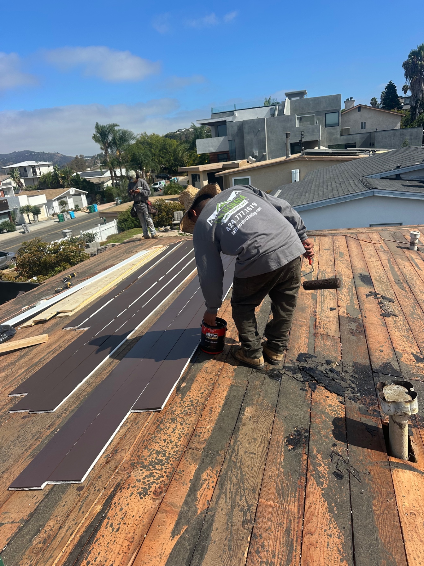 Roofer applying protective coating to new roof boards on an LA home