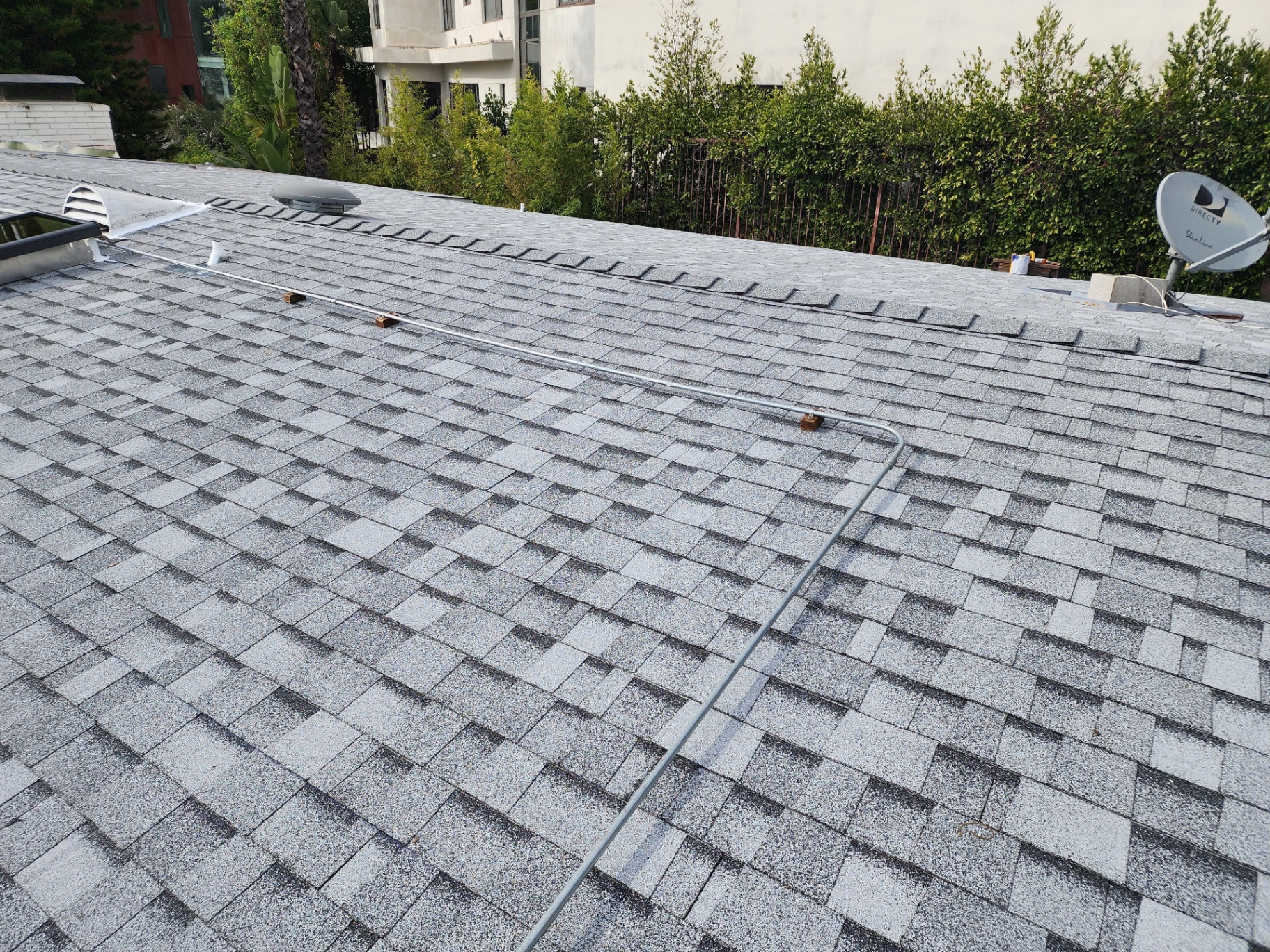 Completed architectural shingle roof with ridge vent and skylight in Los Angeles