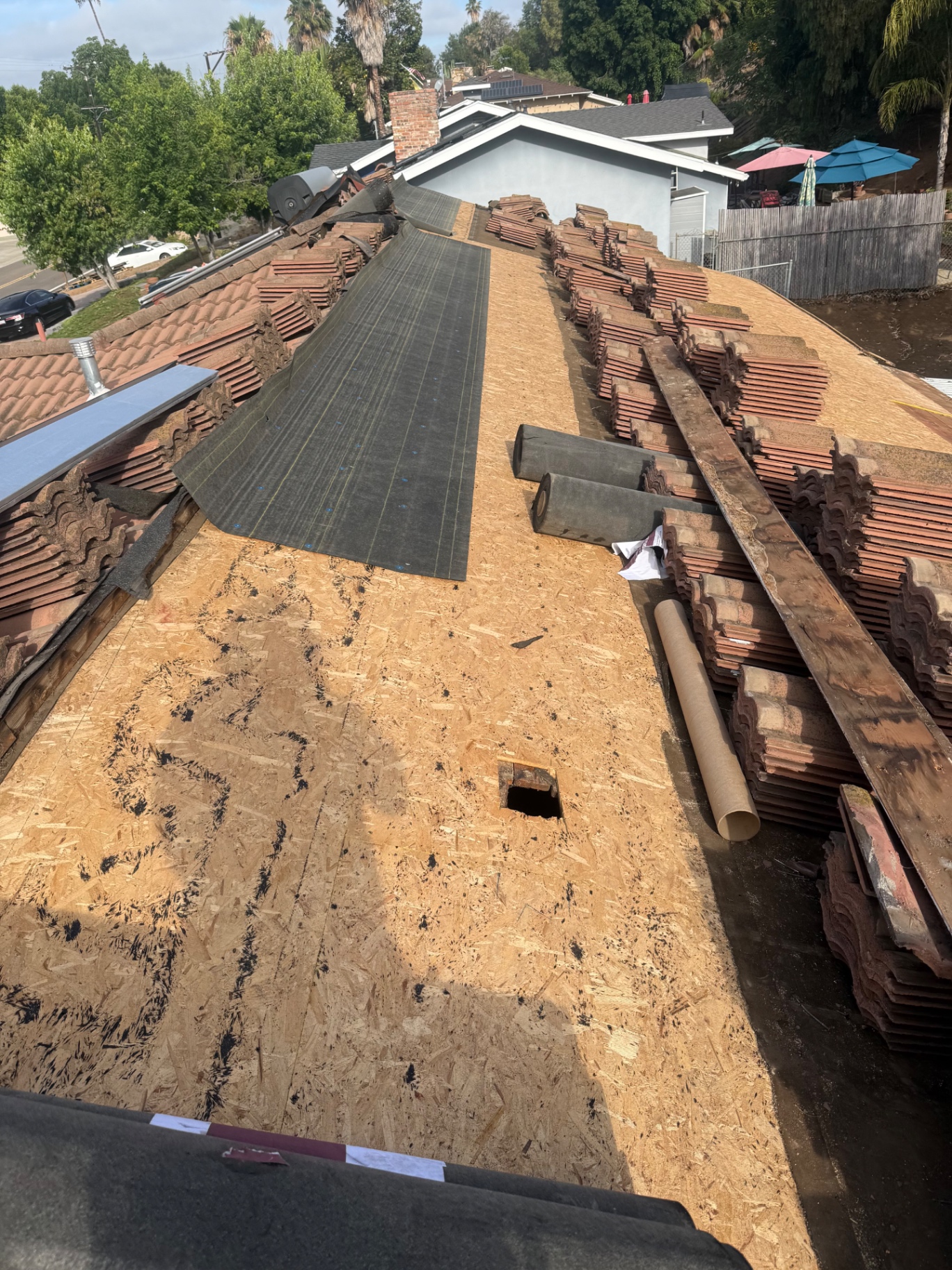 Clay tile roof with underlayment being installed and stacked tiles ready to load