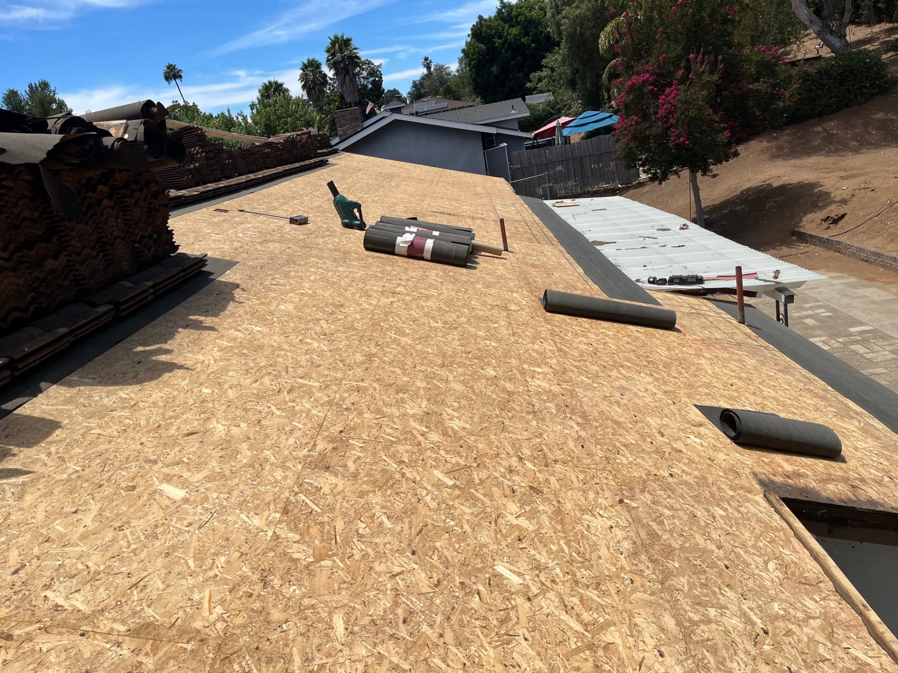 Freshly installed roof decking on a Los Angeles re-roof with tile stacked at the edge