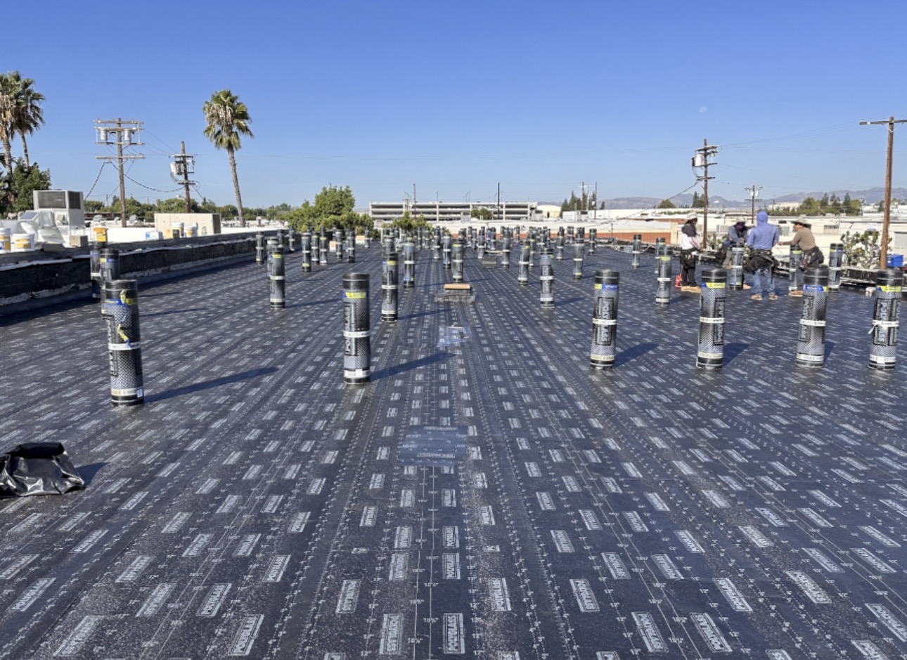 Commercial flat roof in Los Angeles with staged modified bitumen rolls ready for install
