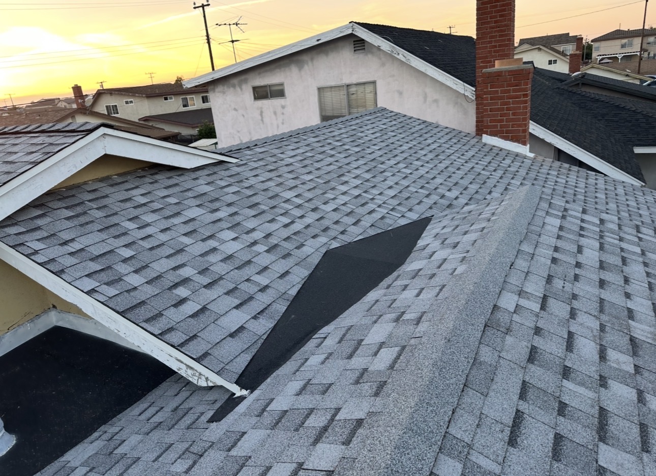Composition shingle roof mid-repair at sunset in a Los Angeles neighborhood