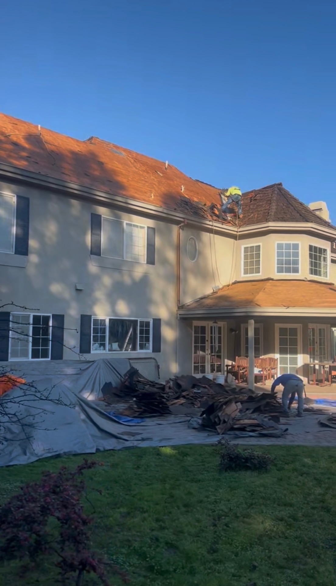 Rear view of an LA home with cedar shake stripped and debris tarped for haul-away