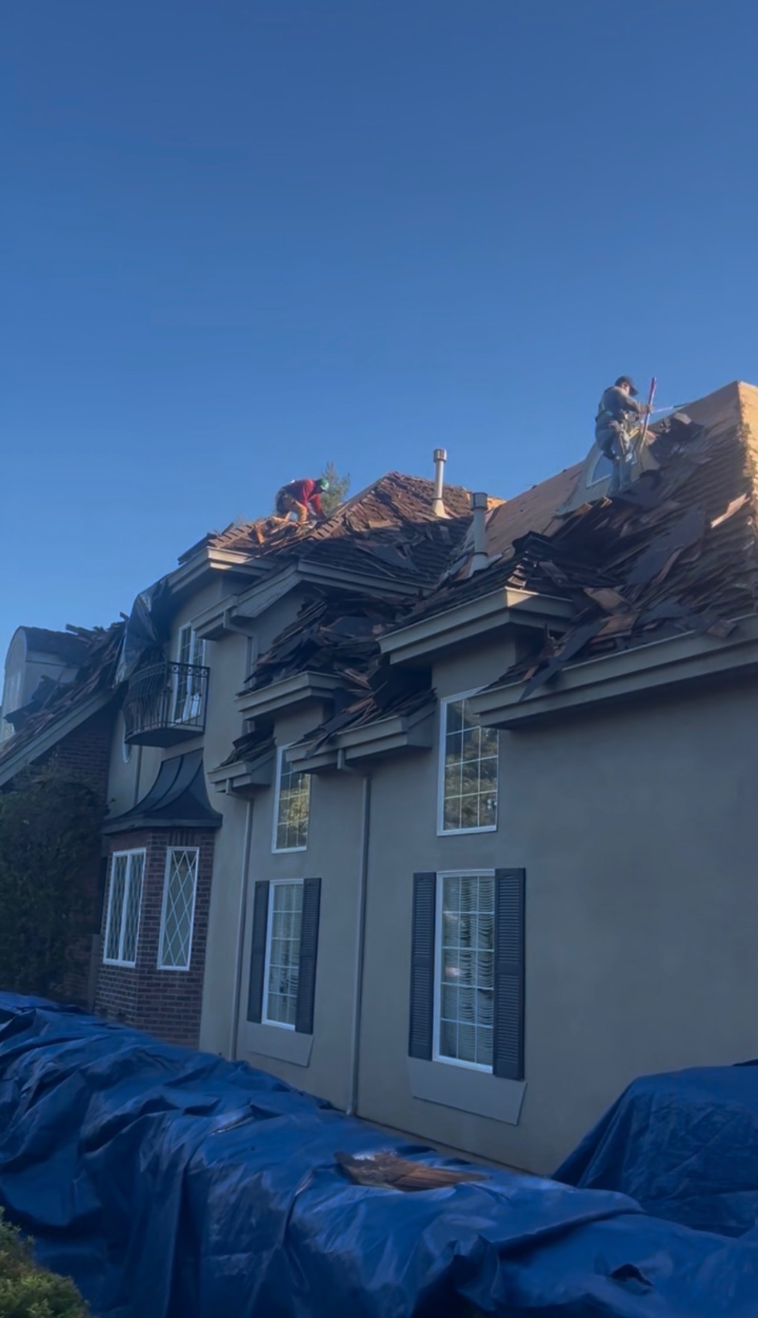 Two-story Los Angeles estate mid tear-off with shake debris covering the roof