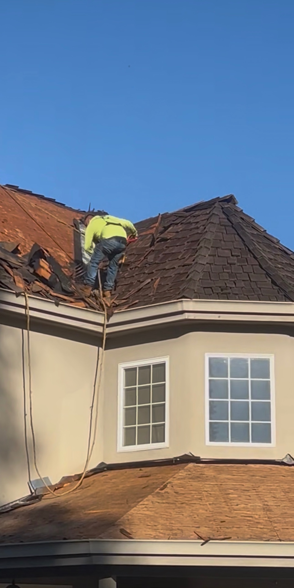Roofer performing a shake tear-off on a luxury Los Angeles turret roof
