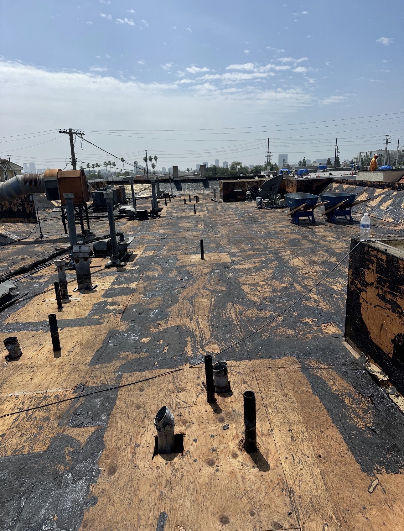 Large flat roof tear-off in progress with downtown Los Angeles skyline in the background